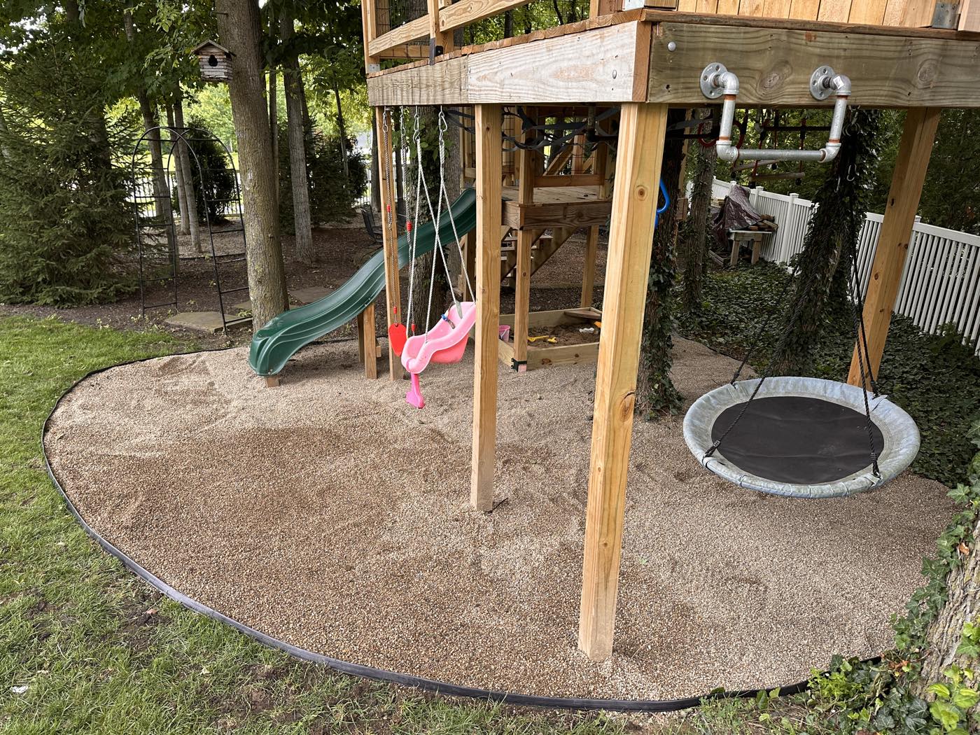 Same playset area filled with clean pea gravel inside fresh edging