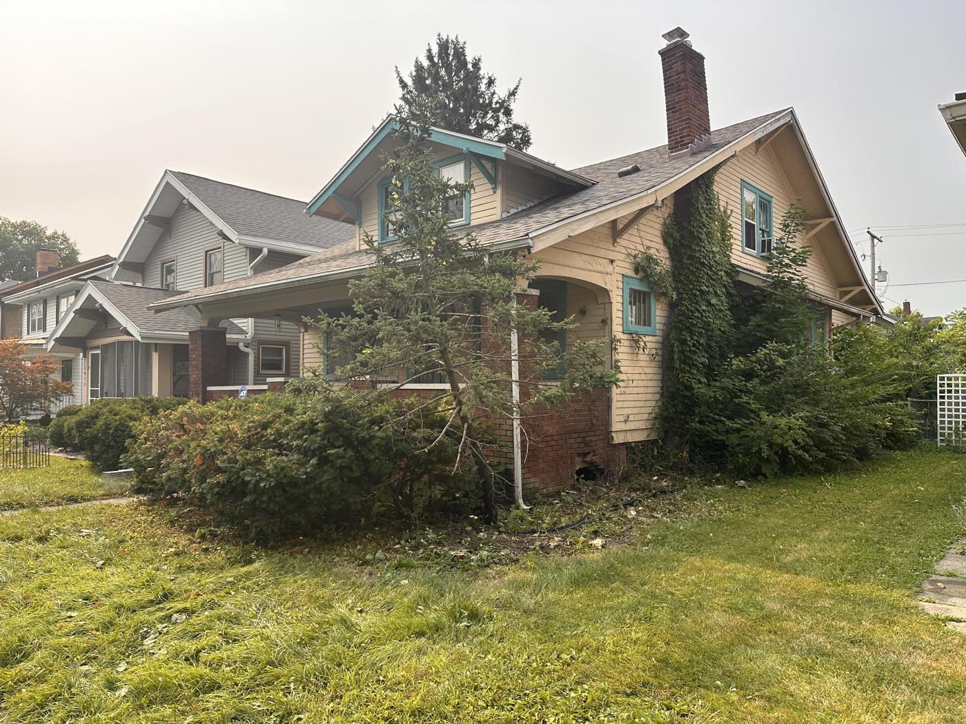 Same house with the overgrowth cut back and the porch visible again