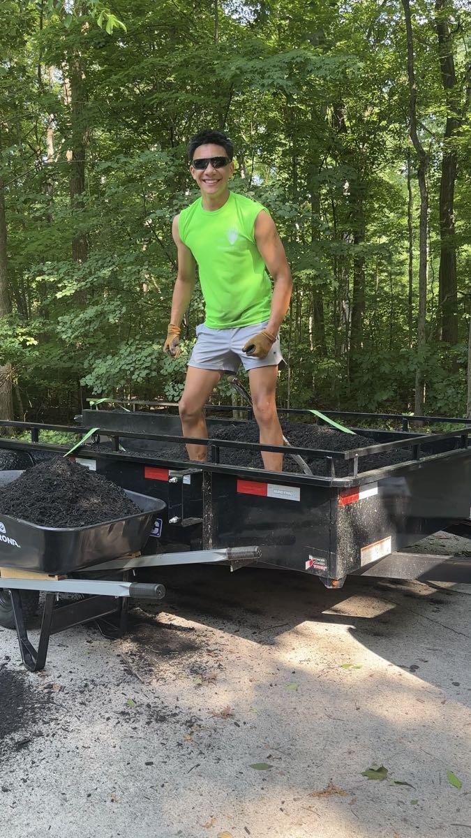 Caleb, founder of Premier Turf Pros, loading mulch on a job site